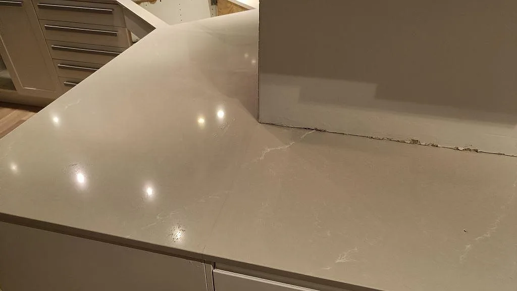Närbild på polerad Silestone Desert Silver komposit i Lund, där köksbänkskivan löper runt ett hörn med ljus ådring.