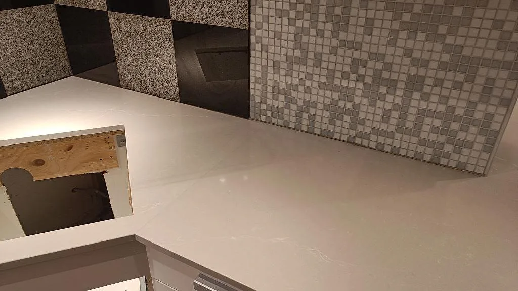 Polerad köksbänkskiva i Silestone Desert Silver i Lund med ljus komposityta och rektangulär öppning i arbetsytan.