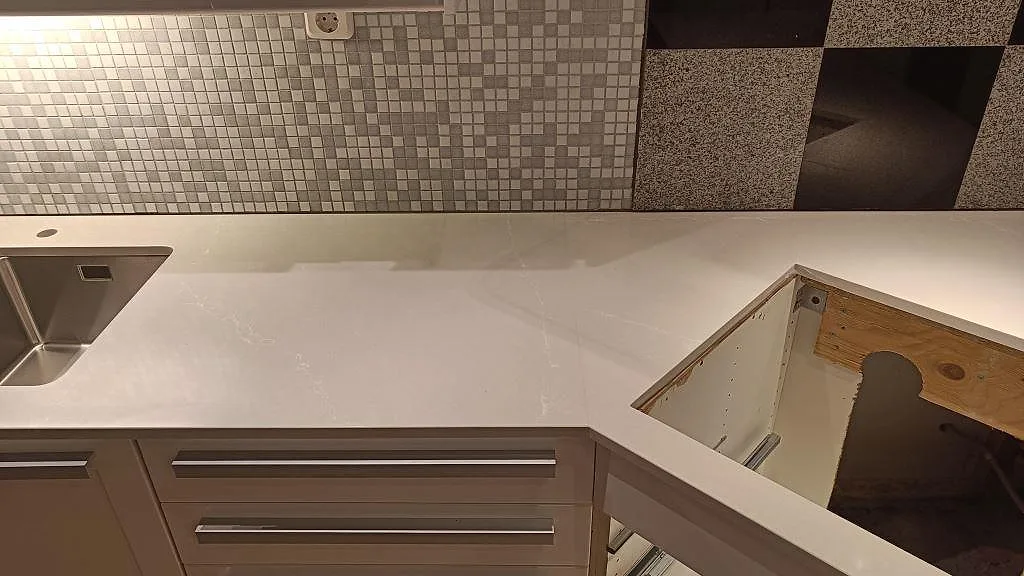 Polerad Silestone Desert Silver köksbänkskiva i komposit i Lund, fotograferad ovanifrån med diskho till vänster och en öppen utskärning i bänken.