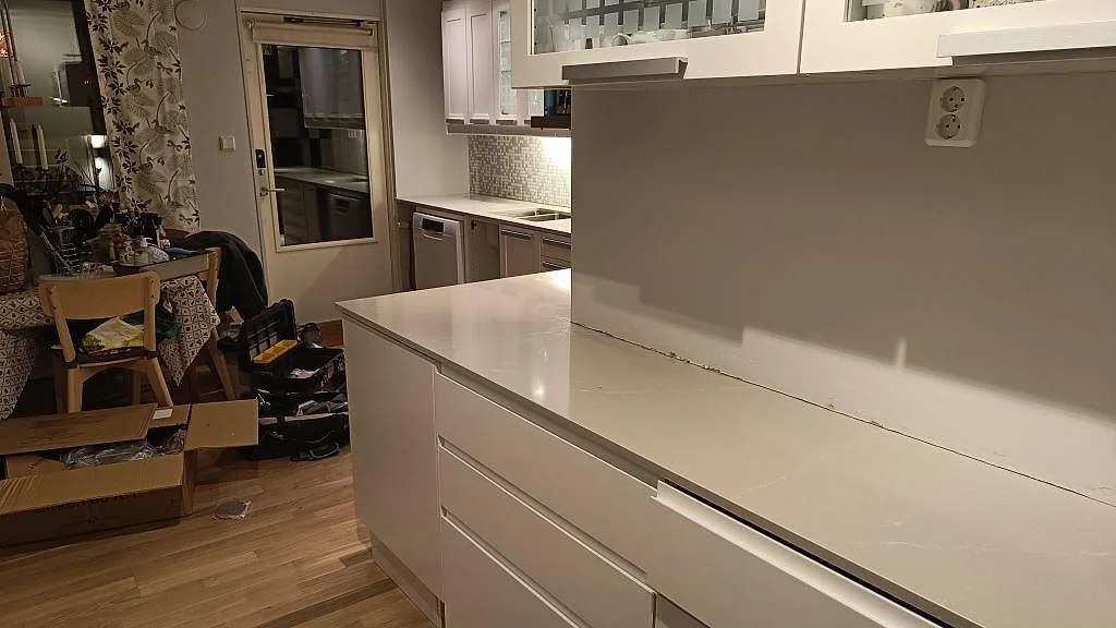 Köksbänkskiva i Silestone Desert Silver, 20 mm polerad komposit, i ett kök i Lund under montering med lång arbetsyta mot vägg.
