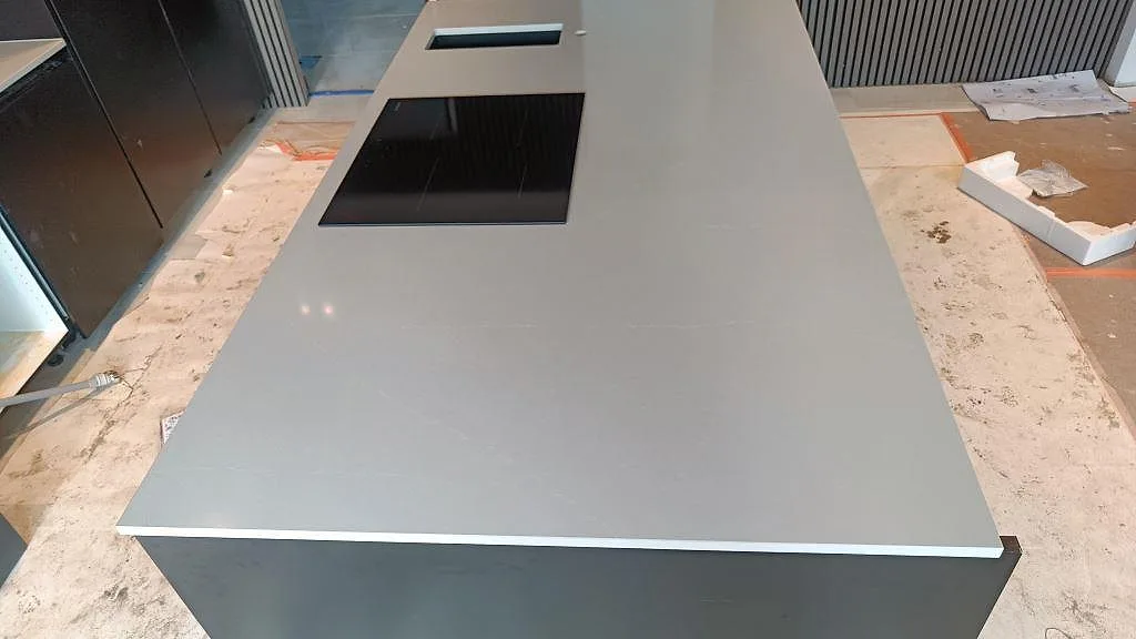 Polerad Silestone Desert Silver som ljus kompositbänkskiva på köksö med infälld häll och diskho i malmö.