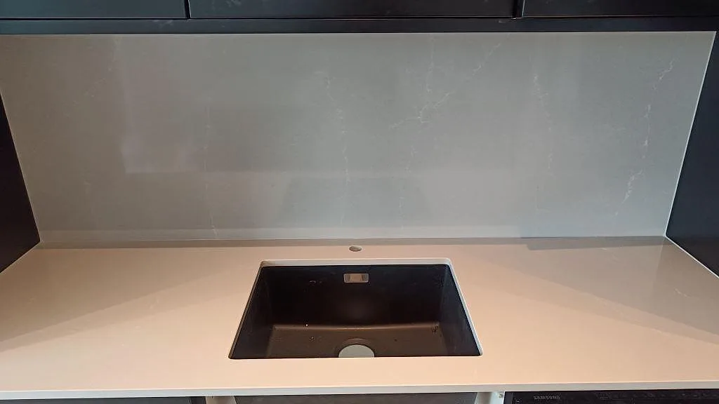 Diskho och fullhögt stänkskydd i polerad Silestone Desert Silver över ljus kompositbänk i malmö.