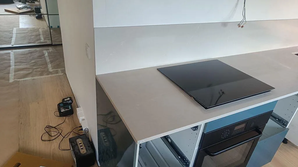 Polerad köksbänkskiva i Silestone Desert Silver med svart induktionshäll och matchande stänkskydd i ett kök i Malmö.