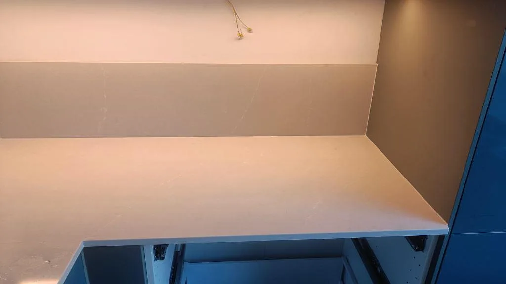 Rak arbetsyta i polerad Silestone Desert Silver med uppvikt stänkskydd och öppen köksstomme i Malmö.