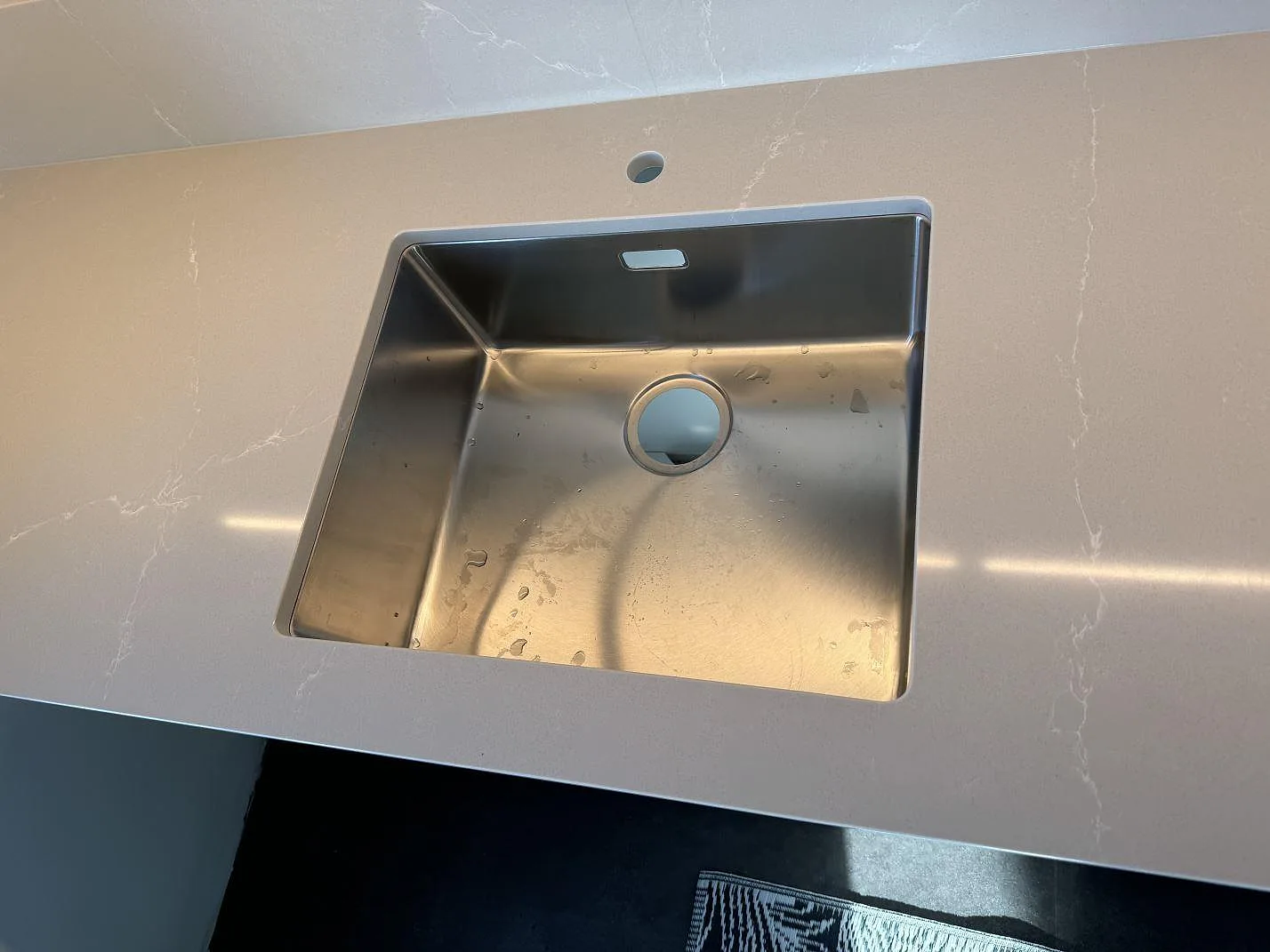 Detalj av rostfri diskho i polerad Silestone Desert Silver med ljusgrå ådring i ett kök i Malmö.