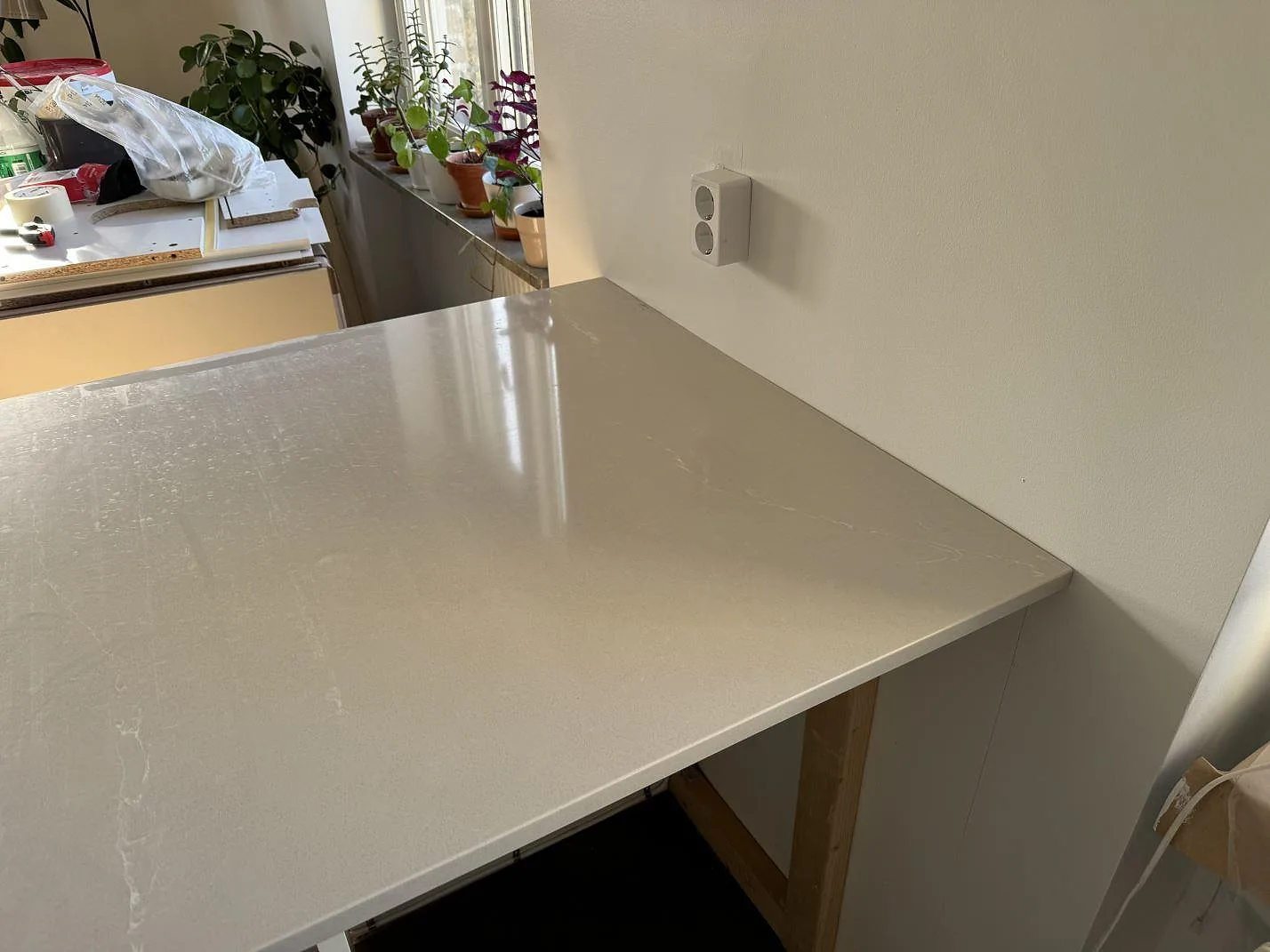 Ljusgrå Silestone Desert Silver som polerad köksbänkskiva mot vägg, fotograferad under montering i Malmö.