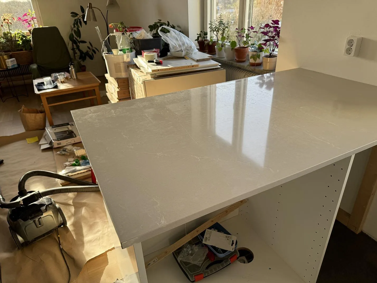 Polerad bänkskiva i Silestone Desert Silver på köksstommar under montering i ett ljust kök i Malmö.