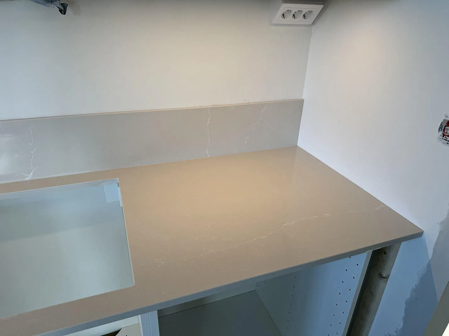 Polerad Silestone Desert Silver som köksbänkskiva med uppvikt stänkskydd och urtag i ett kök under montering i Malmö.
