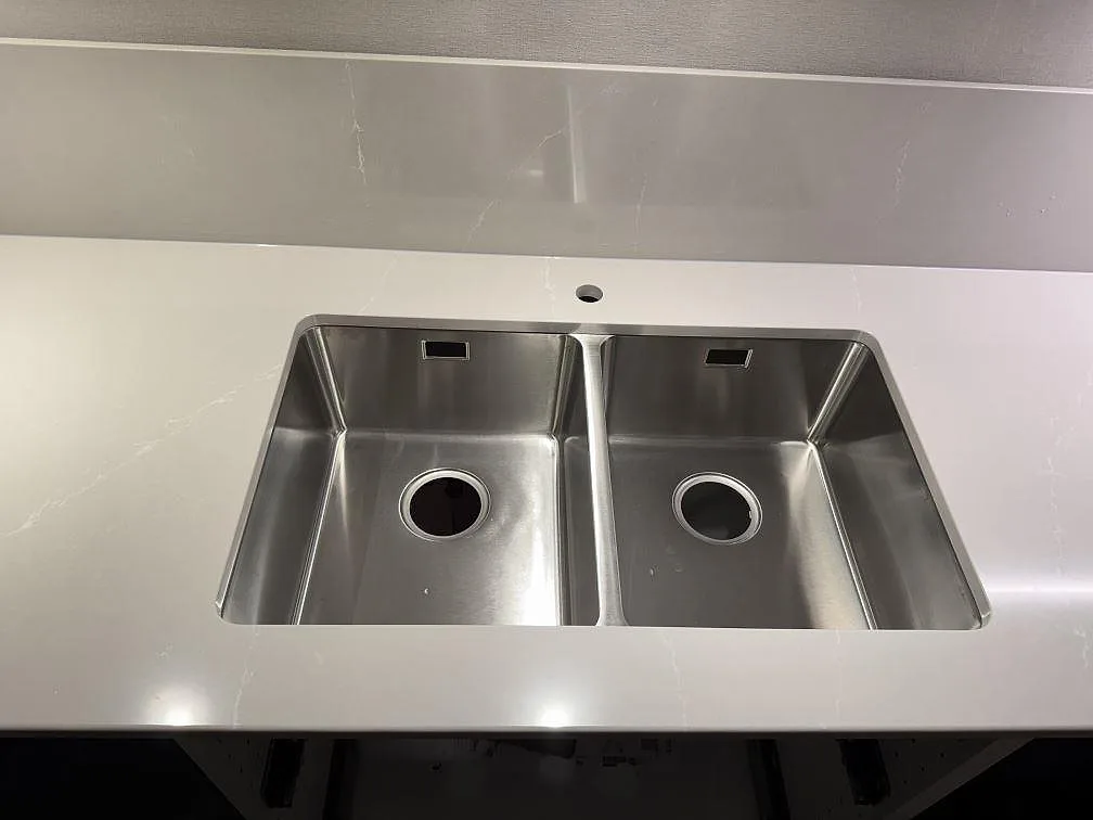 Närbild på rostfri dubbelho i polerad Silestone Desert Silver med ljus ådring och låg stänkkant i Ödåkra.