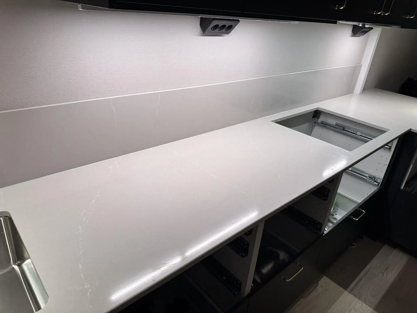 Lång arbetsyta i 20 mm polerad Silestone Desert Silver med förberett hällurtag och matchande stänkskydd i Ödåkra.