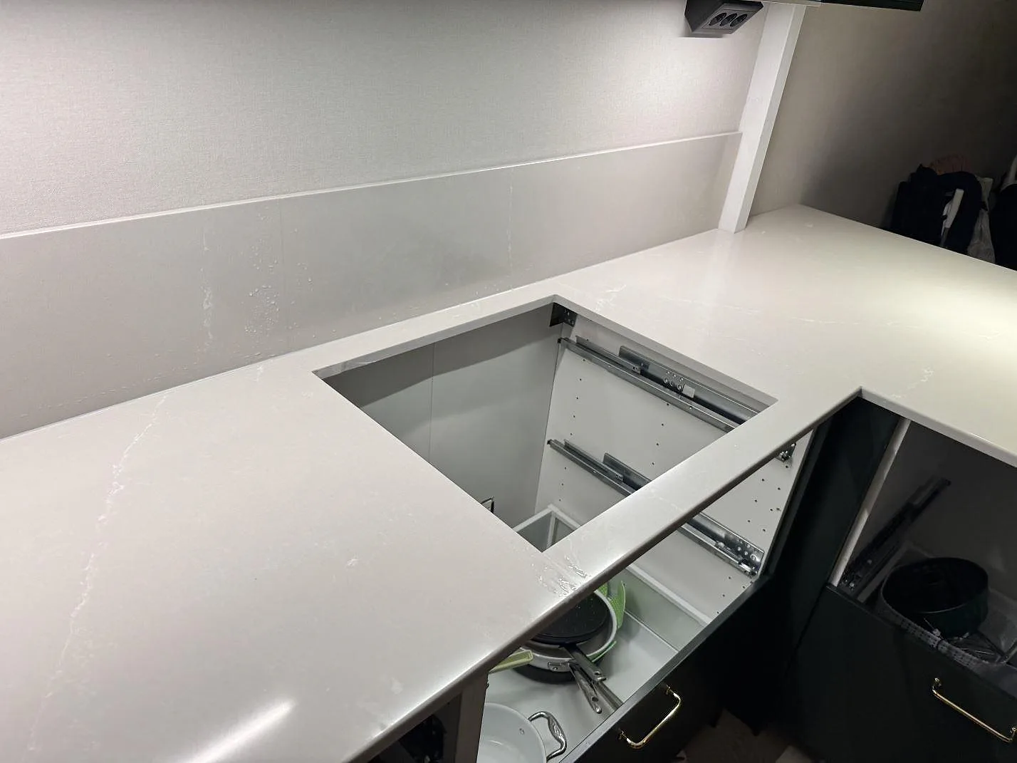 Detalj av hällurtag i 20 mm polerad Silestone Desert Silver-bänkskiva med låg stänkkant bakom i Ödåkra.