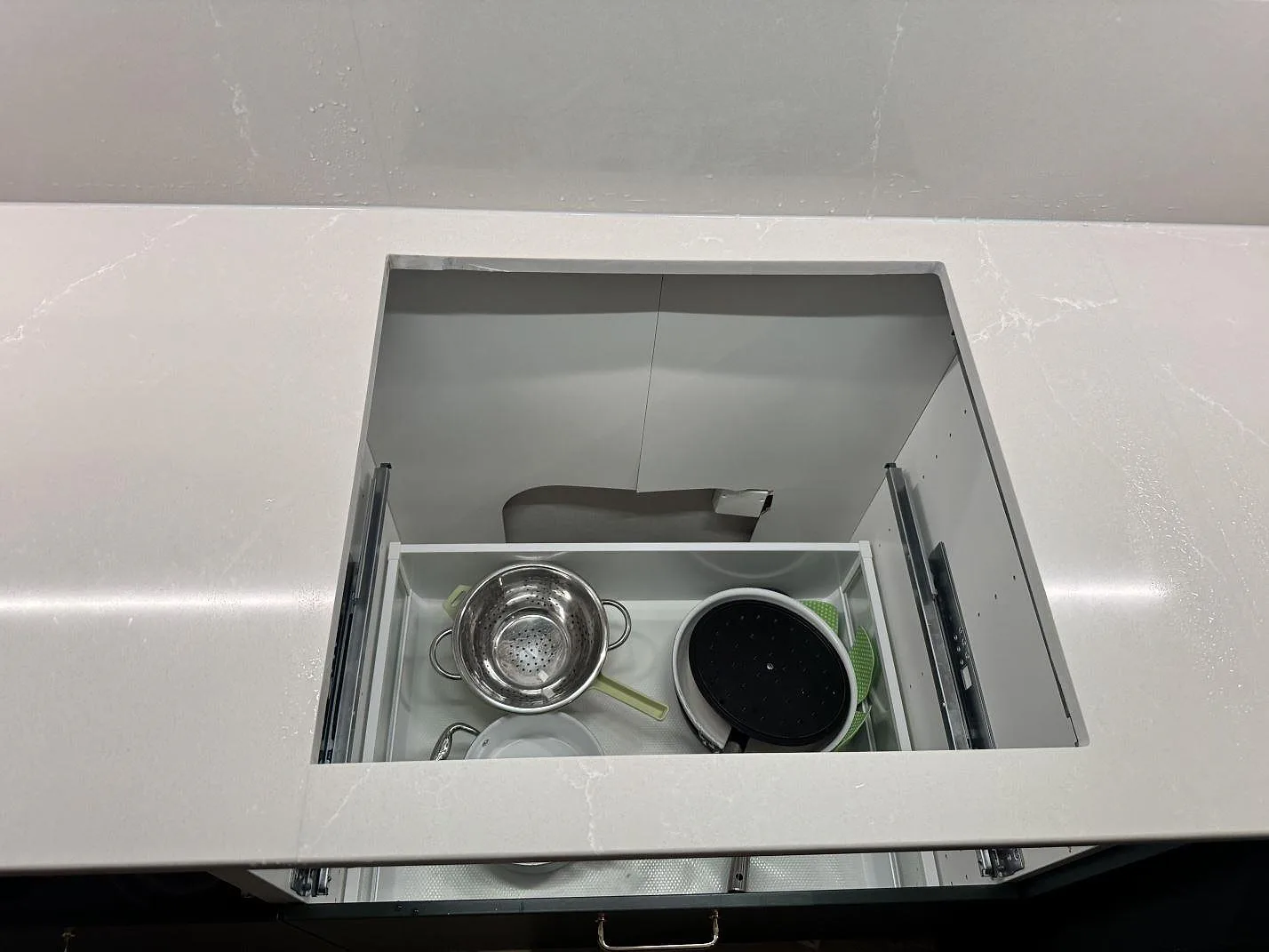 Topvy över rektangulärt hällurtag i polerad Silestone Desert Silver-komposit med synliga lådskenor under i Ödåkra.