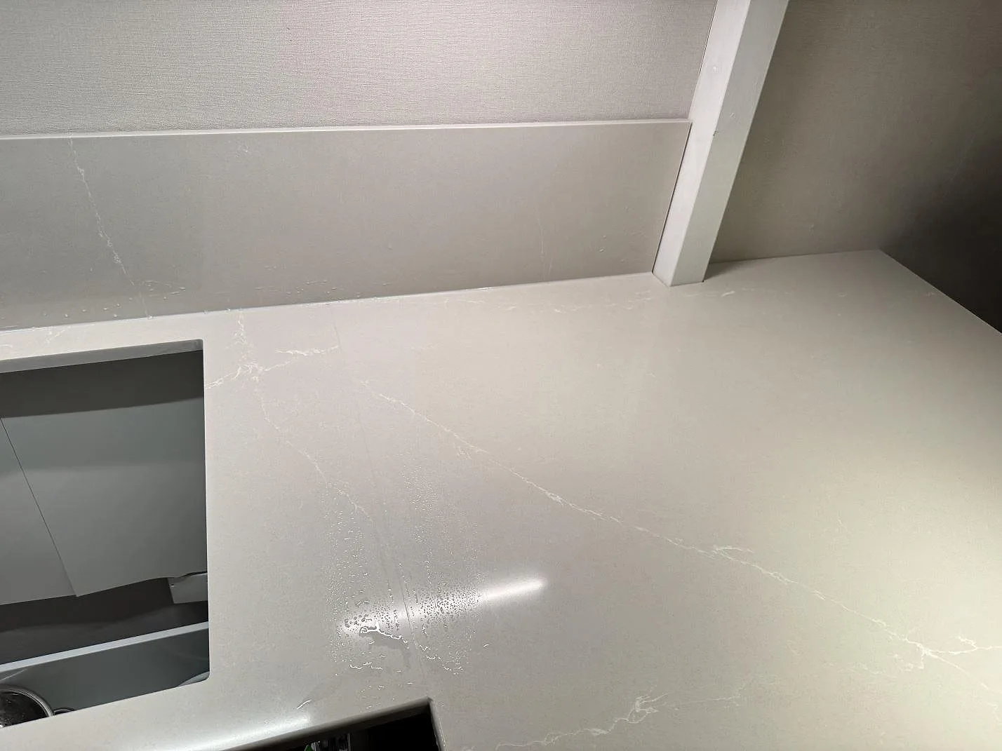 Närbild på ljus ådring och blank yta i polerad Silestone Desert Silver bredvid hällurtaget i Ödåkra.