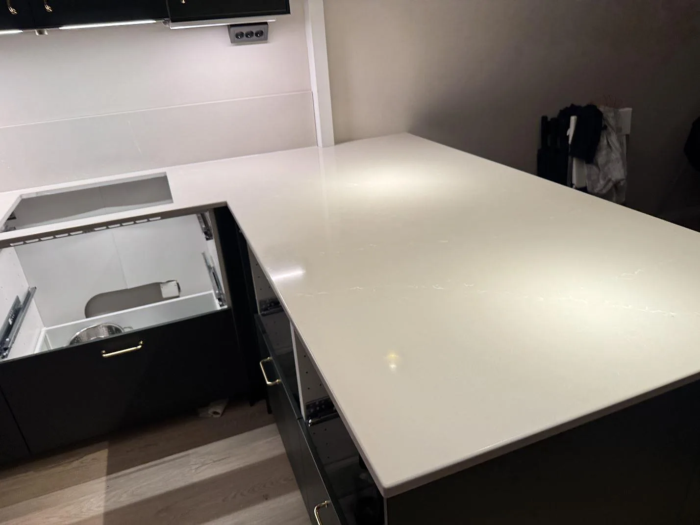 Köksbänk i polerad Silestone Desert Silver-komposit med bred hörnyta, hällurtag och öppna köksstommar i Ödåkra.