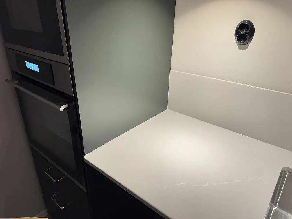 Sidoyta vid ugnstorn med polerad bänkskiva och låg stänkkant i Silestone Desert Silver i köket i Ödåkra.