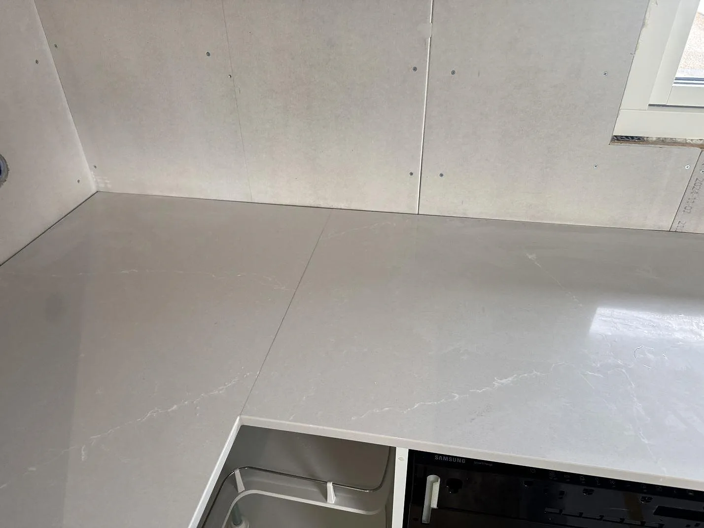 Närbild på polerad Silestone Desert Silver, komposit, som köksbänkskiva med ljusa vener i Sandared.