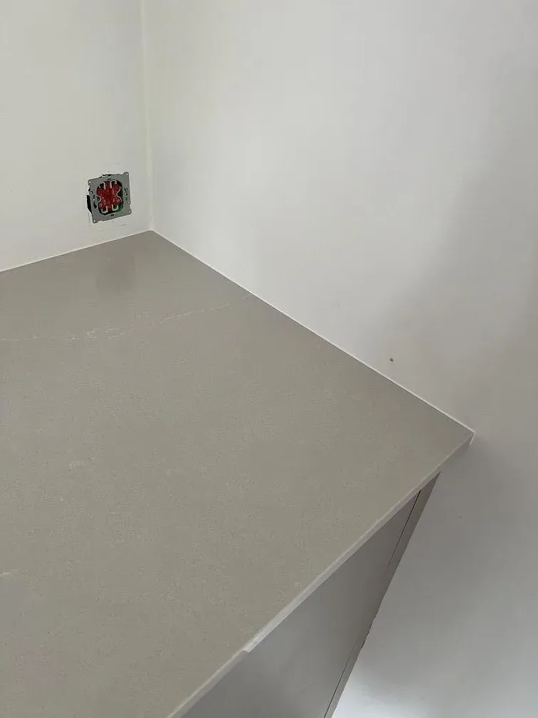 Hörn på en polerad Silestone Desert Silver bänkskiva med ljus komposityta och rak kant i Skanör.