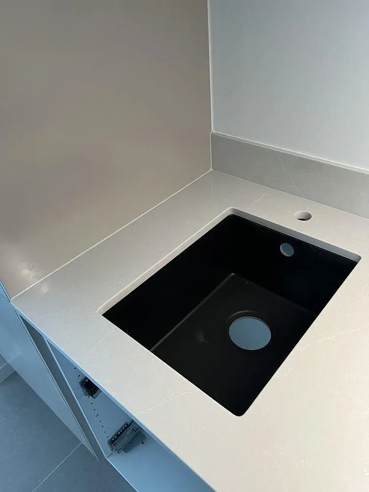 Diskhozonen i en polerad Silestone Desert Silver bänkskiva med ljus ådring och svart ho i Skanör.
