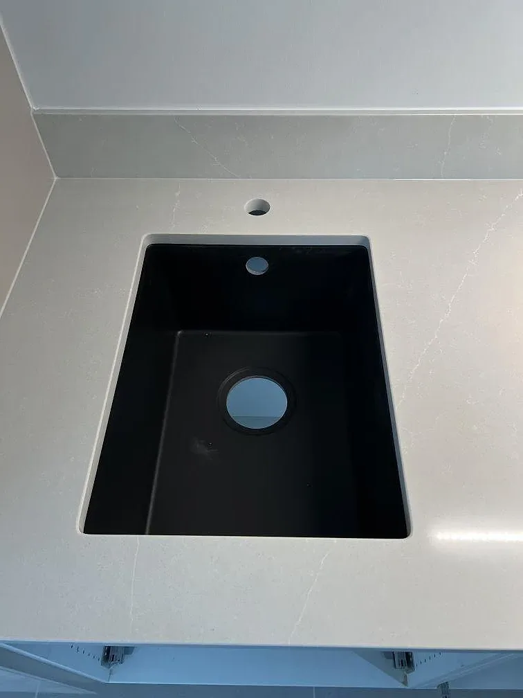 Närbild på svart diskho i ljus Silestone Desert Silver, polerad komposit, med uppvikt stänkkant i Skanör.