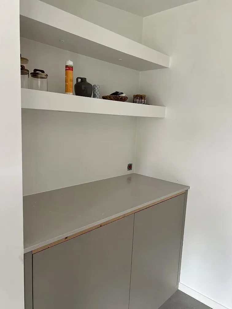 Installerad sidobänk i polerad Silestone Desert Silver med ljus ådring och hyllor ovanför i Skanör.
