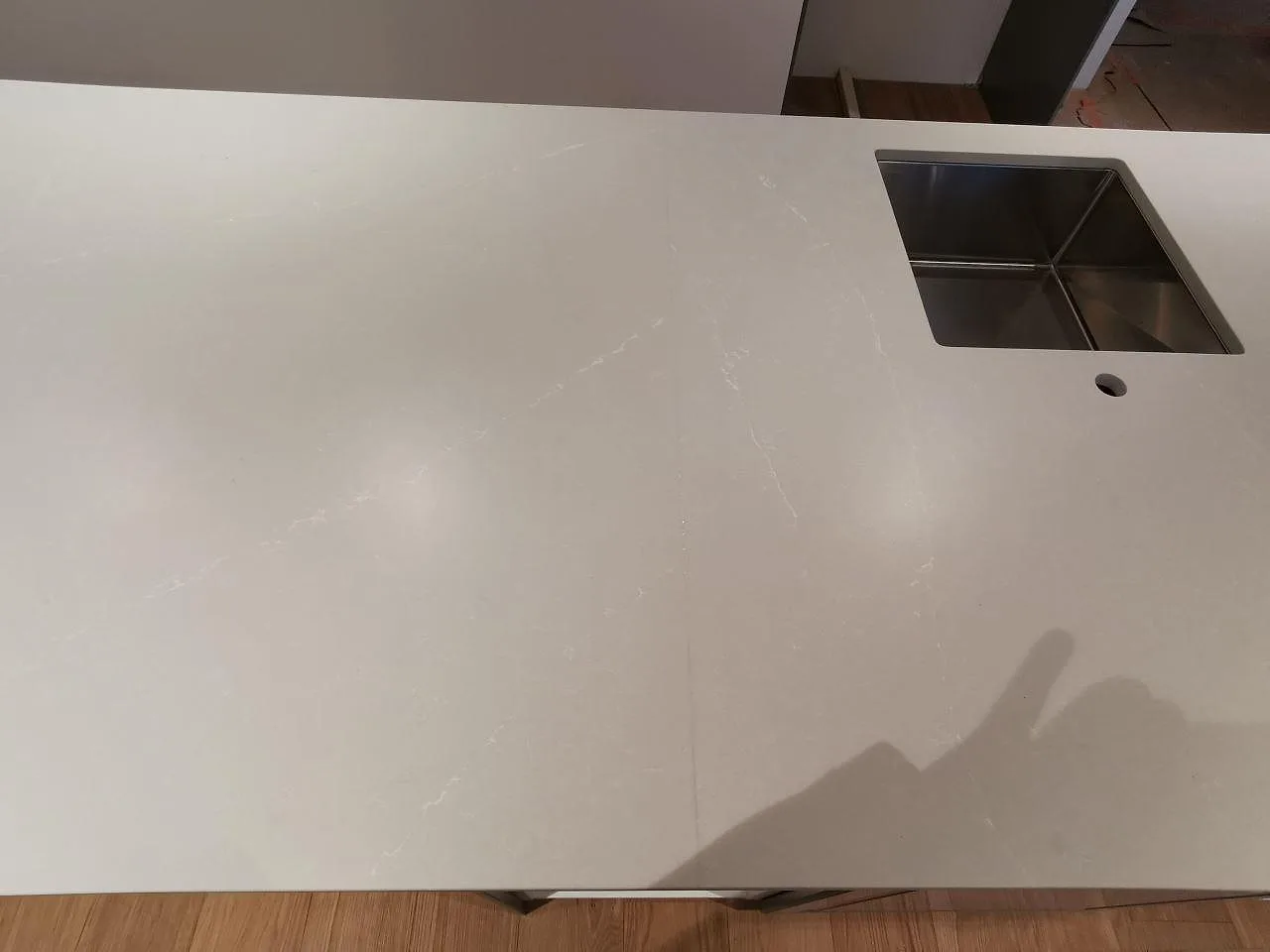 Underlimmad rostfri diskho och blandarehål i en bänkskiva av Silestone Desert Silver i ett kök i Skivarp.