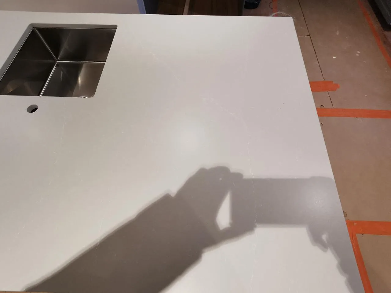Bänkskiva i matt Silestone Desert Silver med underlimmad rostfri diskho i ett kök under montering i Skivarp.