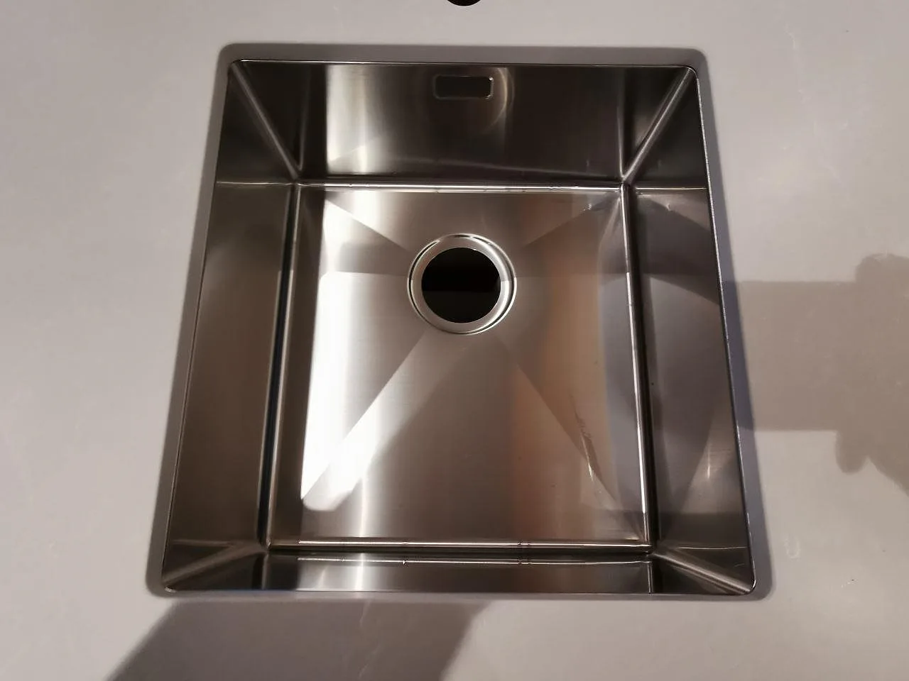 Underlimmad rostfri diskho av Strand i en bänkskiva av Silestone Desert Silver i ett kök i Skivarp.