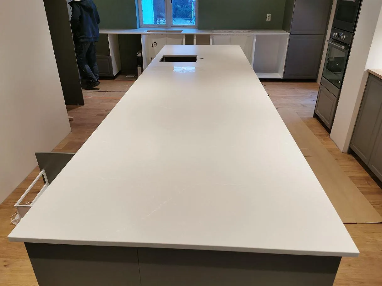 Köksbänkskiva och köksö i Silestone Desert Silver, matt Mocka, i ett kök under montering i Skivarp.