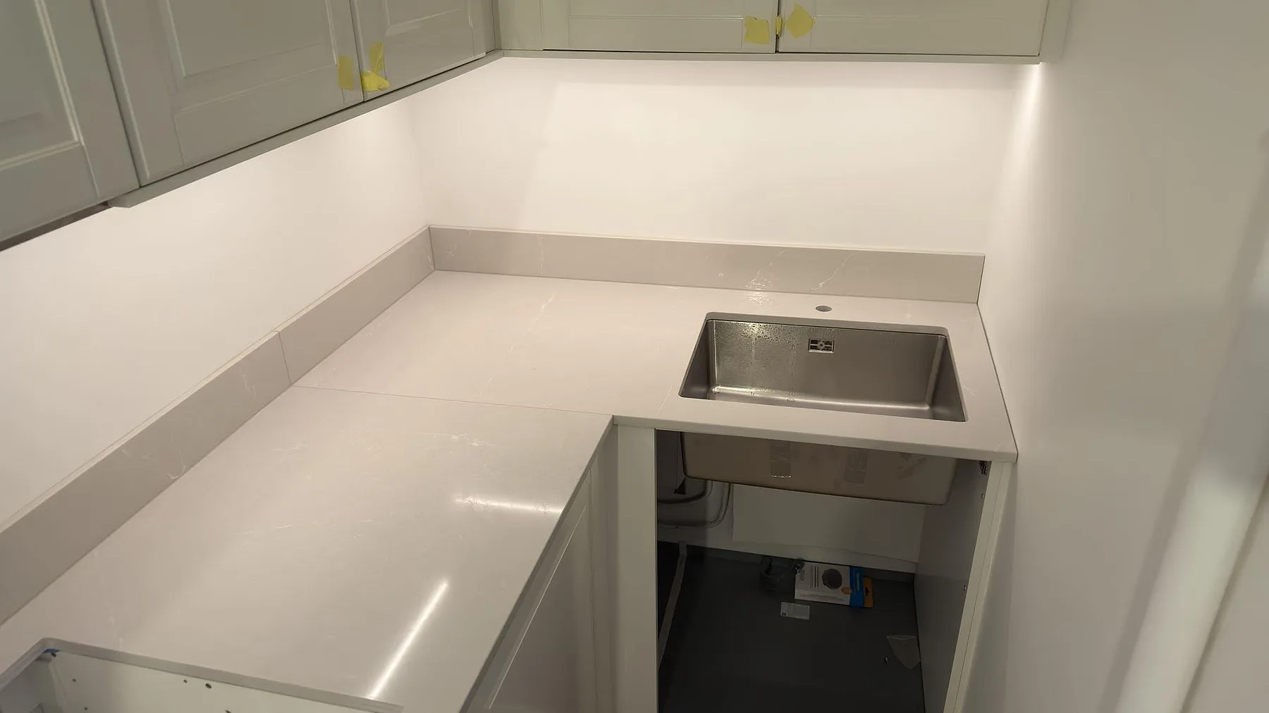 Diskbänksdel i polerad Silestone Desert Silver med rostfri diskho och låg stänkkant i köket i Stockholm.