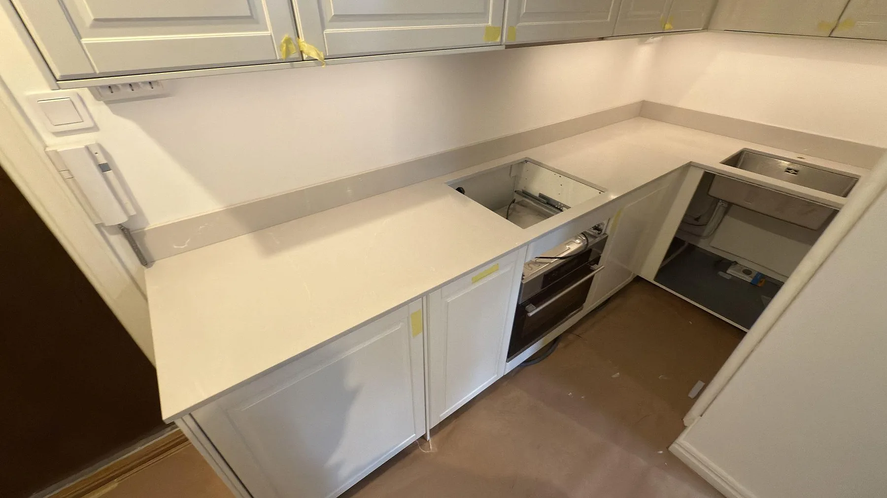 Köksbänkskiva i polerad Silestone Desert Silver, 20 mm komposit, med låg stänkkant och urtag för häll i ett kök i Stockholm.