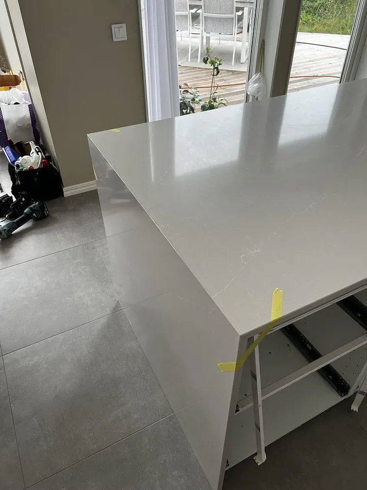 Närbild av polerad Silestone Desert Silver komposit på en köksö med ljus ådring och fönsterljus i Svedala.