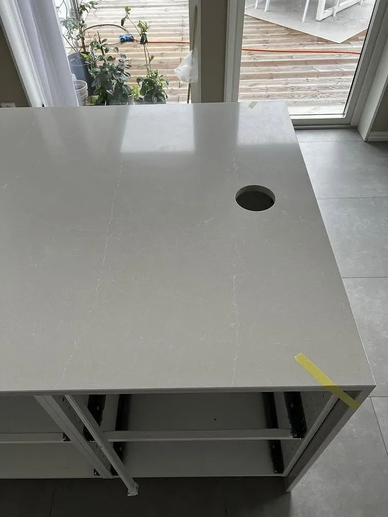 Sidovy av köksö i Silestone Desert Silver, polerad ljus komposit, med öppen stomme och rund detalj i Svedala.
