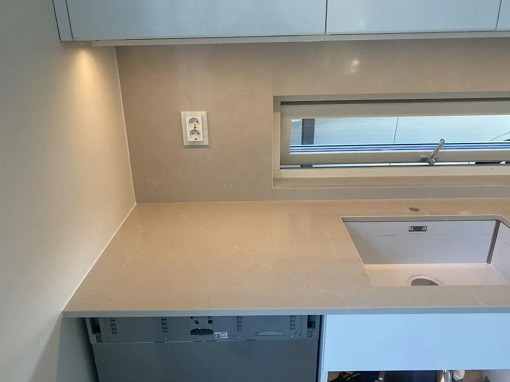 Hörn med underlimmad diskho i polerad Silestone Desert Silver bänkskiva och stänkskydd i ett kök i Tygelsjö.