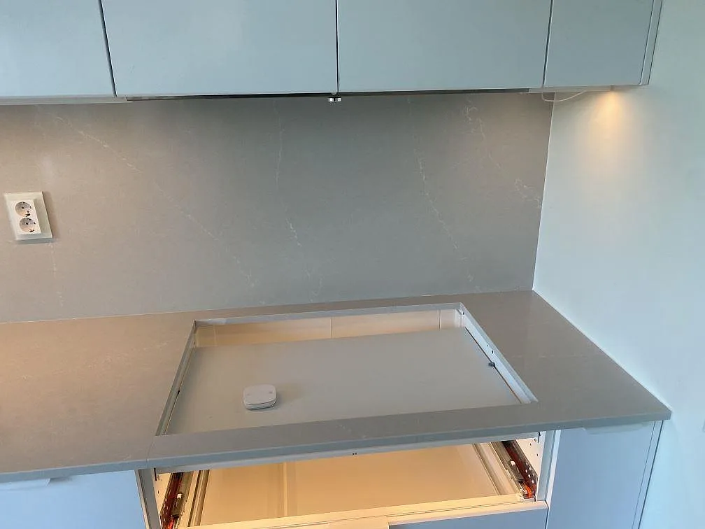 Urtag för häll i bänkskiva av polerad Silestone Desert Silver med stänkskydd i ett kök i Tygelsjö.