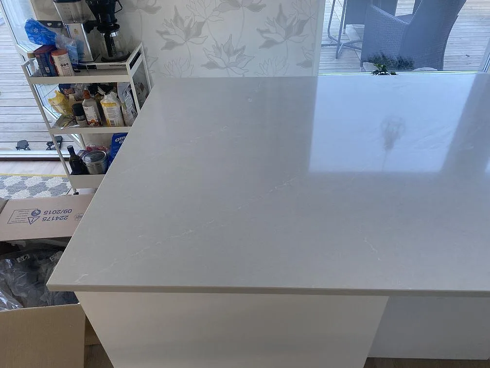 Köksö i polerad Silestone Desert Silver, ljus gråbeige kvartskomposit, i ett kök i Tygelsjö.