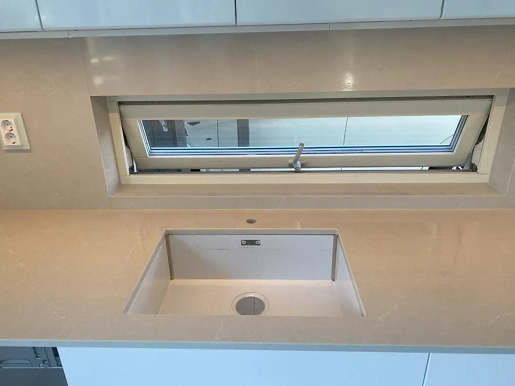 Underlimmad diskho i bänkskiva av Silestone Desert Silver under fönstret i ett kök i Tygelsjö.