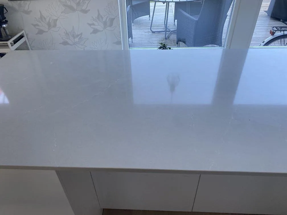 Köksö med polerad bänkskiva i Silestone Desert Silver, ljus gråbeige komposit, i ett kök i Tygelsjö.