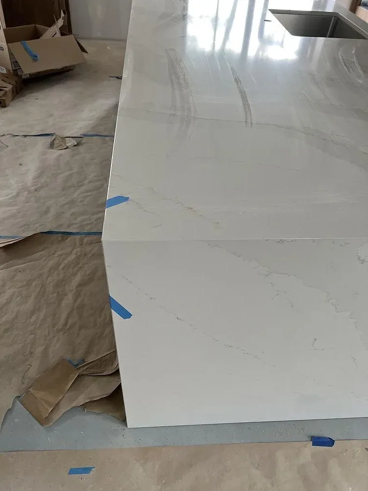 Installerad köksö i polerad Silestone Eternal Calacatta Gold med vit yta, diskho och skyddad arbetsyta under montering i Åhus.