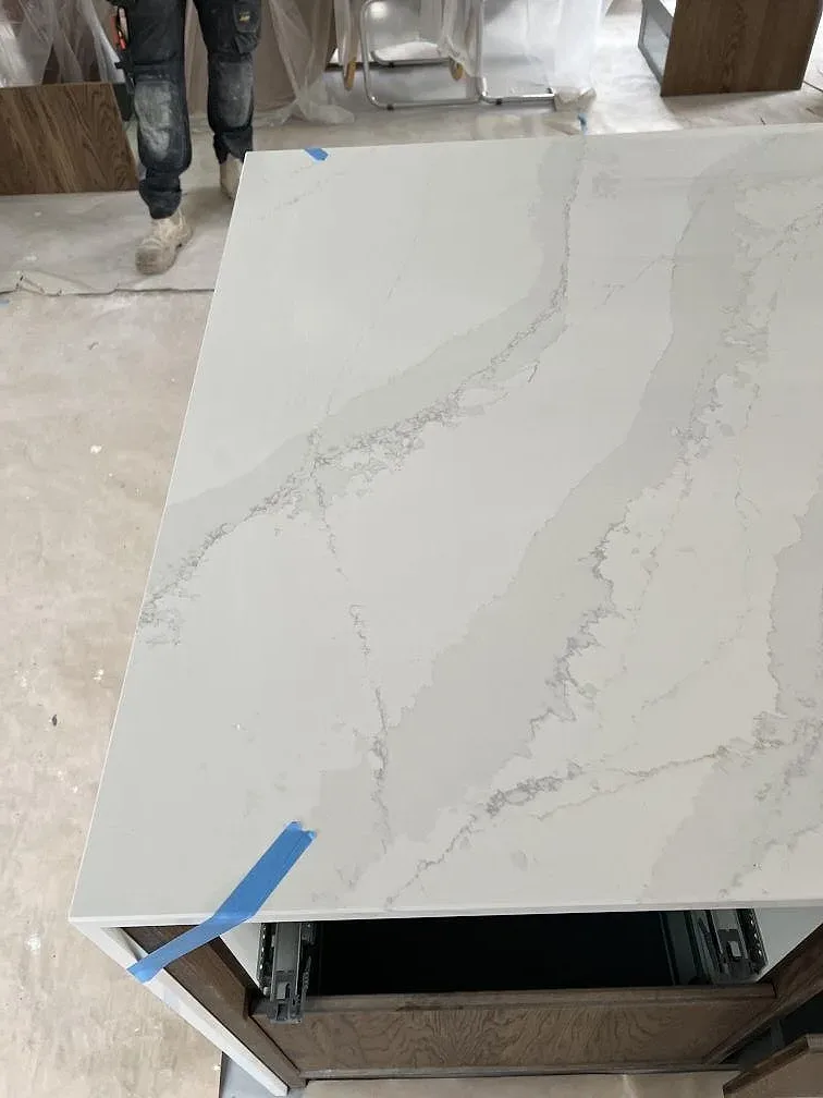 Topvy av köksö i polerad Silestone Eternal Calacatta Gold med marmorerad ådring och monteringsarbete i ett kök i Åhus.