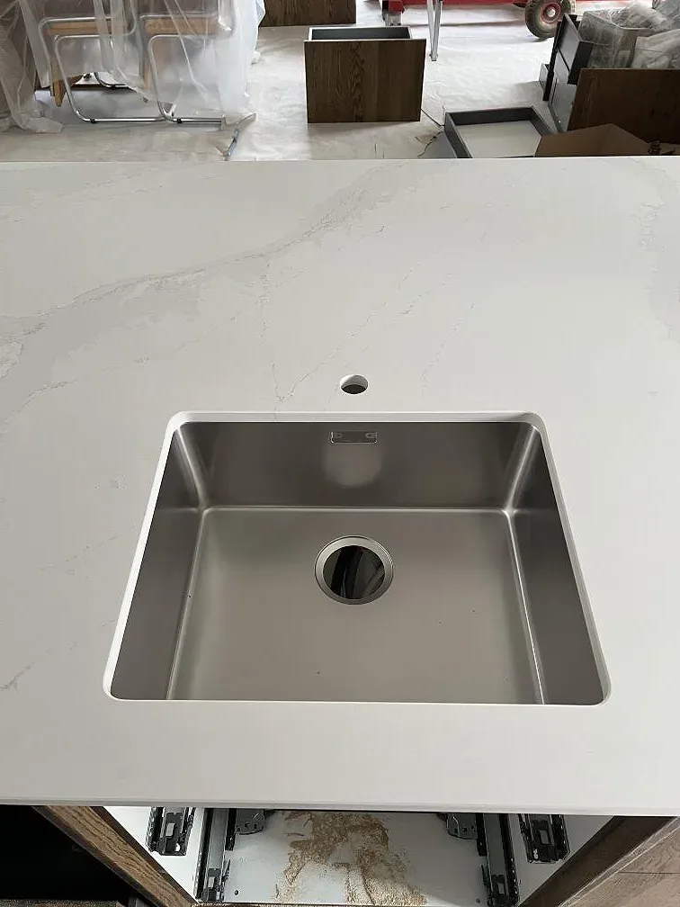 Polerad köksbänkskiva i Silestone Eternal Calacatta Gold med rostfri diskho monterad under stenen i Åhus.