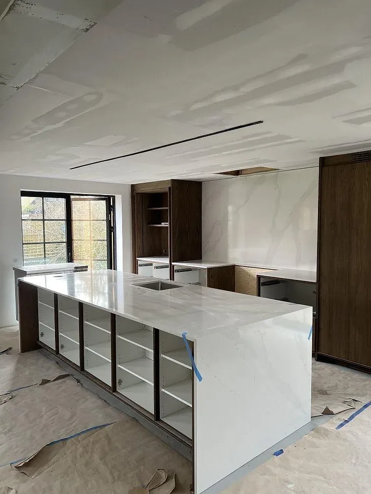 Köksö och bänkskiva i polerad Silestone Eternal Calacatta Gold med vit bas och guldtonad ådring i ett kök i Åhus under montering.