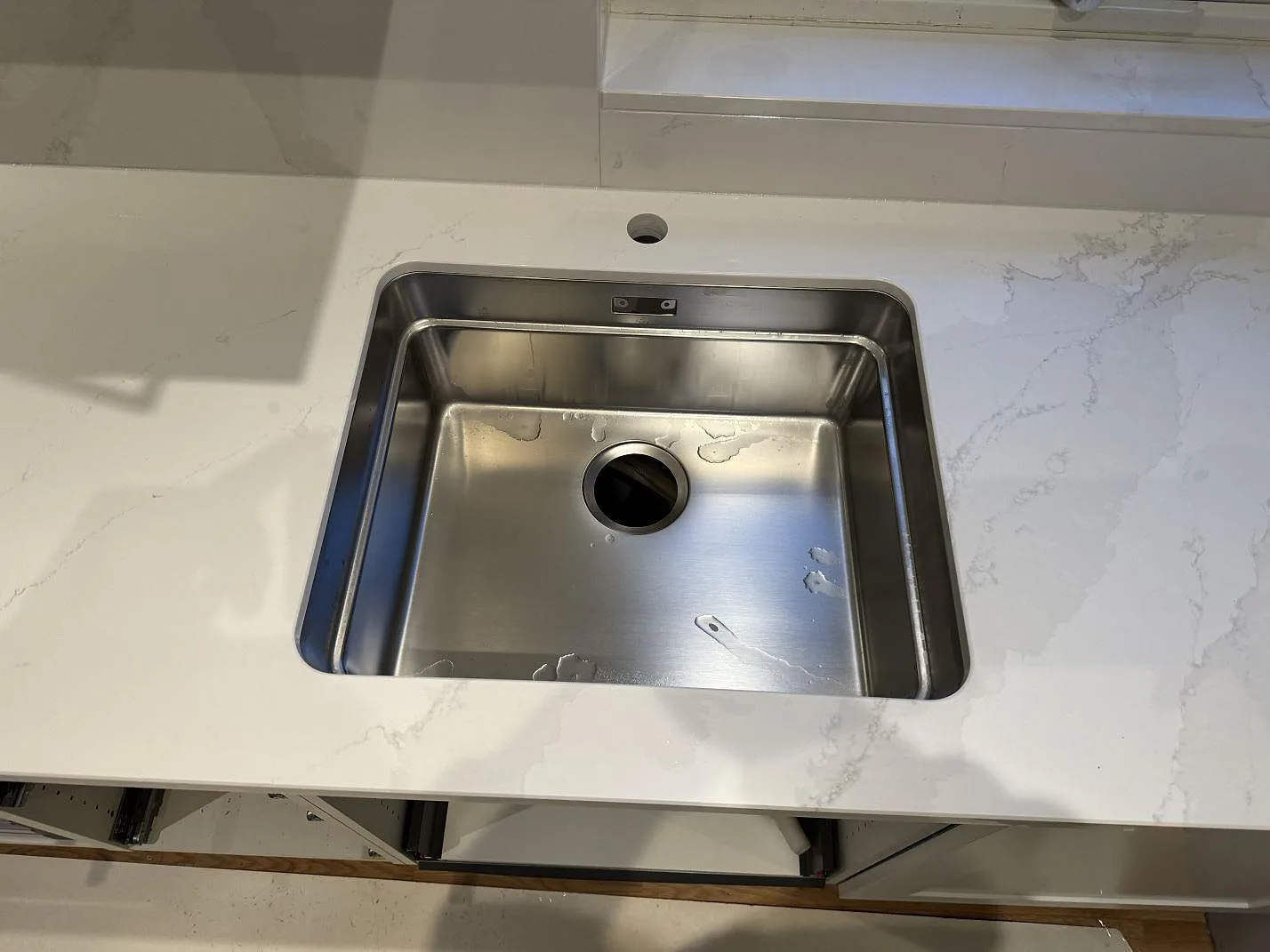 Ovanifrån syns den rostfria diskhon monterad under en polerad Silestone Eternal Calacatta Gold-bänkskiva i Bunkeflostrand.