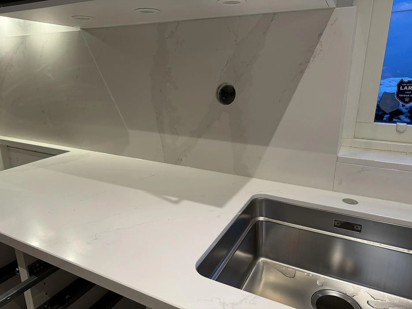 L-formad köksbänkskiva i polerad Silestone Eternal Calacatta Gold med underlimmad rostfri diskho och stänkskydd i Bunkeflostrand.