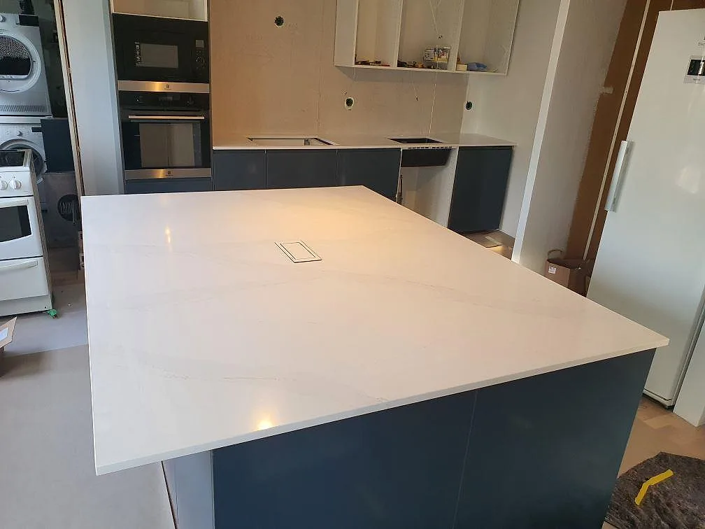 Köksbänkskiva och stor köksö i vit Silestone Eternal Calacatta Gold, polerad 20 mm komposit, under montering i ett kök i Flen.