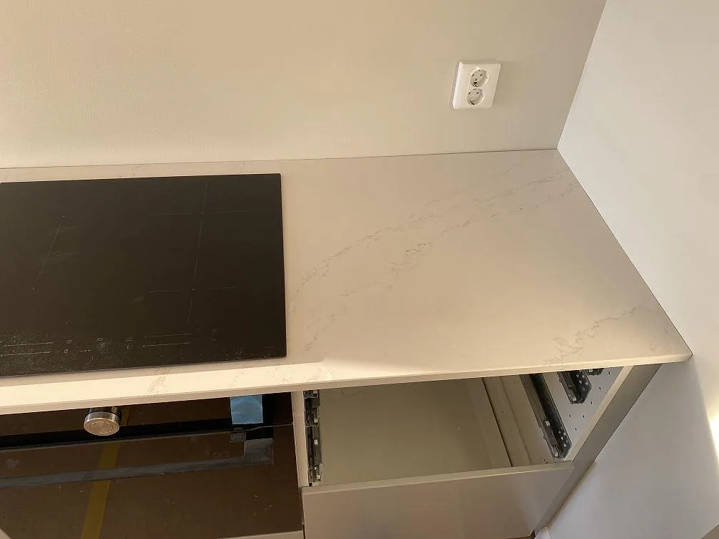 Polerad köksbänkskiva i Silestone Eternal Calacatta Gold med plats för häll och tydlig grå och guldaktig ådring i ett kök i Halmstad.