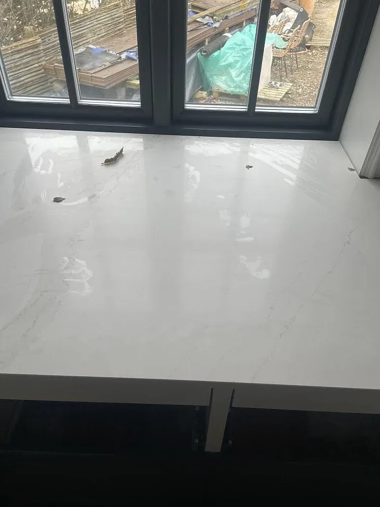 Polerad yta på Silestone Eternal Calacatta Gold mot ett fönster, där reflektionen visar den blanka finishen i ett kök i Hornbæk.