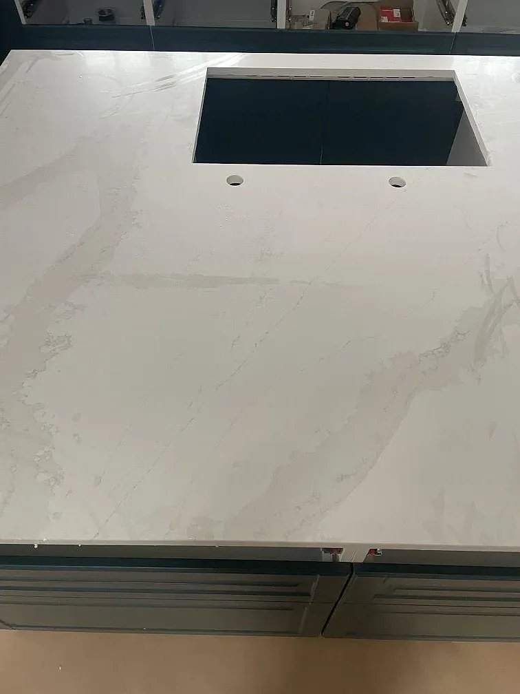 Köksbänkskiva i vit Silestone Eternal Calacatta Gold med borrade hål för köksblandare, sedd ovanifrån under montering i Hornbæk.