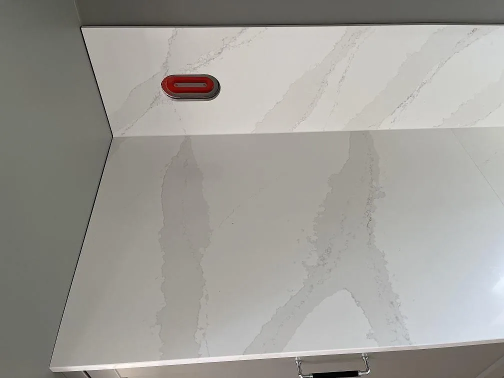 Köksbänkskiva i Silestone Eternal Calacatta Gold med uppvikt stänkskydd och eluttag, polerad yta med Calacattaådring, i Löddeköpinge.