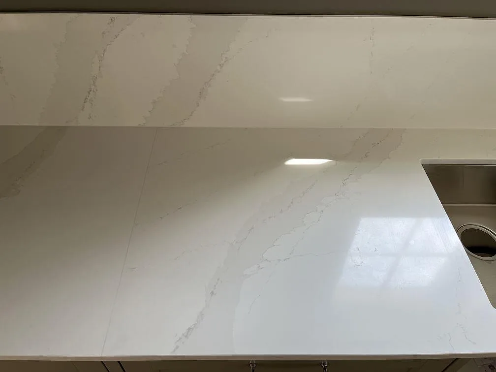 Polerad köksbänkskiva i Silestone Eternal Calacatta Gold med uppvikt stänkskydd och underlimmad diskho i Löddeköpinge.