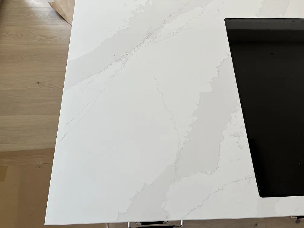 Köksö i polerad Silestone Eternal Calacatta Gold med infälld svart induktionshäll och tydlig grå och guldfärgad Calacattaådring i Löddeköpinge.